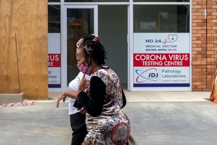 Afrique du Sud – 11 juin 2020 : deux femmes africaines portant des masques passent devant le centre de test de dépistage pour la Covid-19.