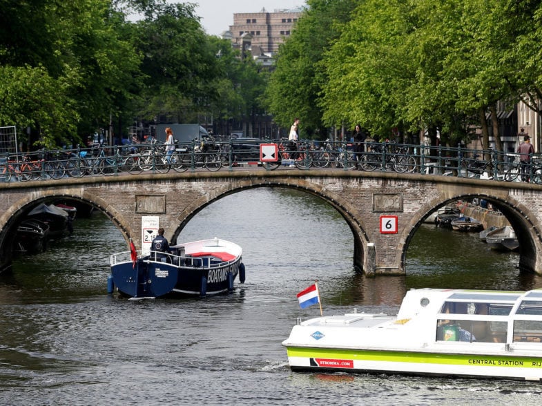 FILE PHOTO: Tourists boats pass on a canal in Amsterdam, Netherlands, May 16, 2018. Picture taken May 16, 2018. REUTERS/Francois Lenoir/File Photo
