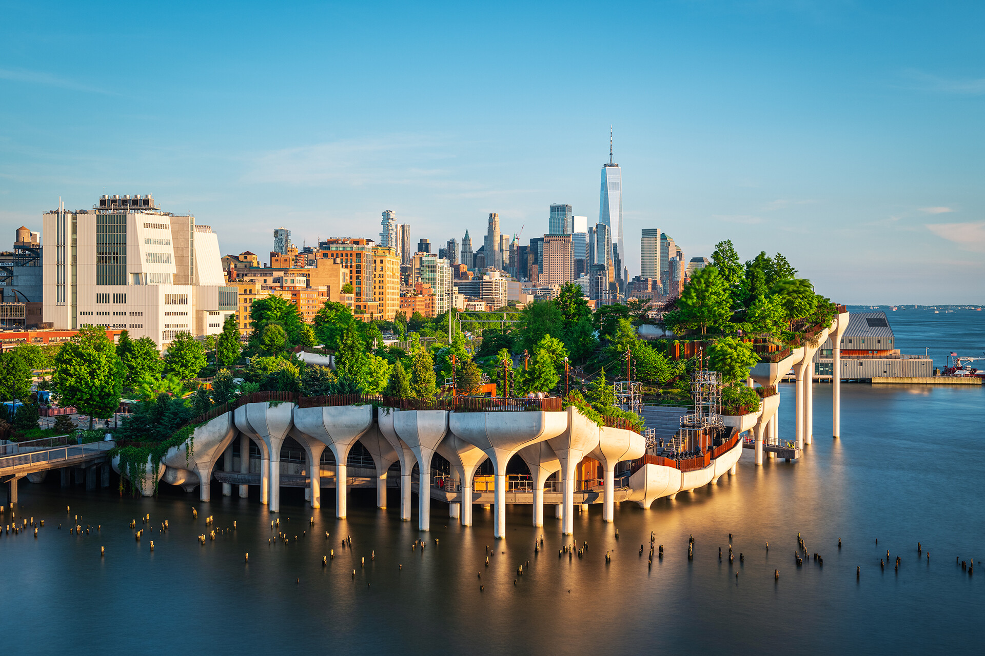 Long exposure of Little Island over the Hudson River in Chelsea, New York, with the lower Manhattan skyline as a stunning backdrop at dusk.