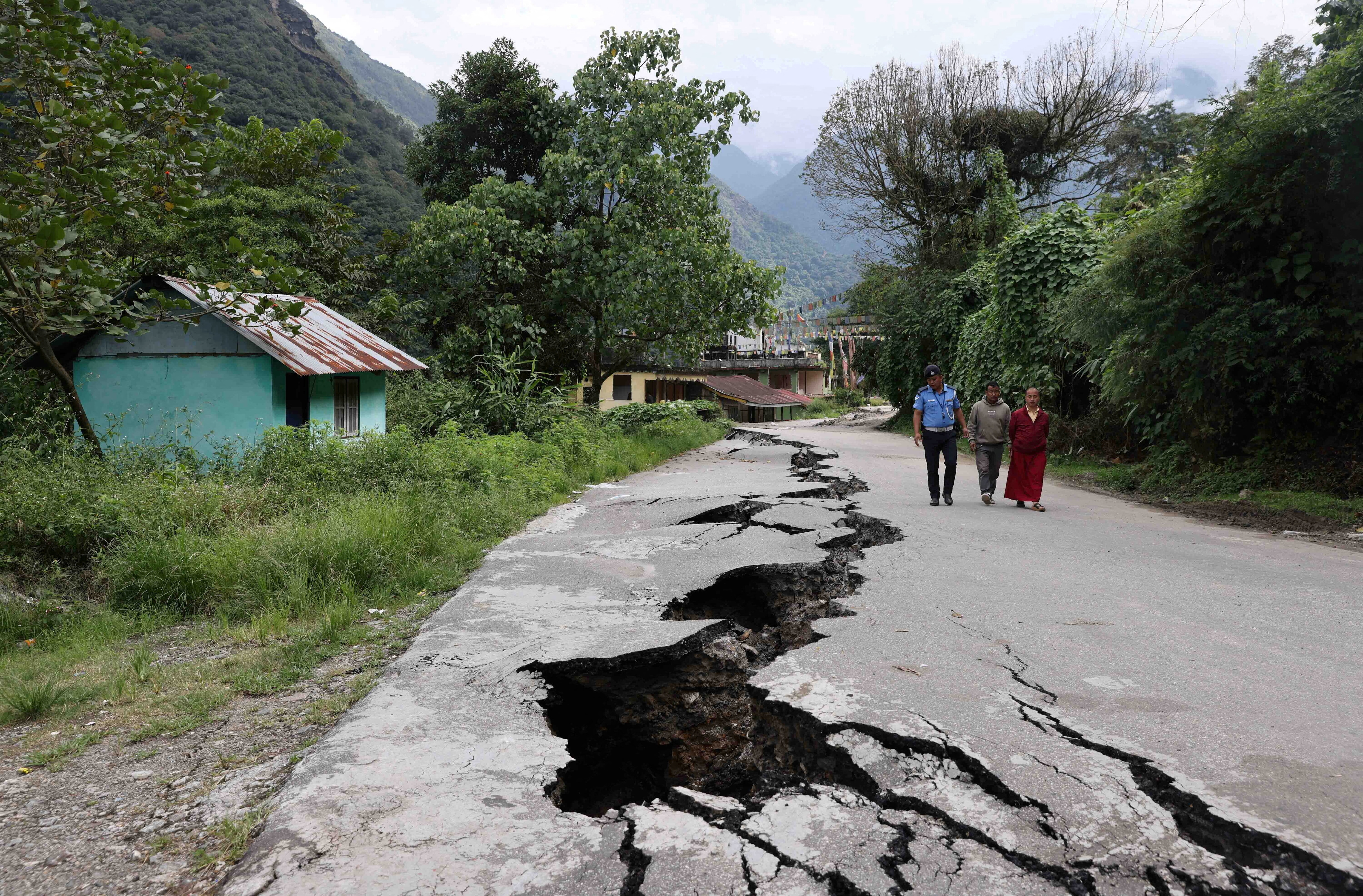 People walk along a road with cracks caused by flash floods in Naga-Namgor village, Sikkim, India, October 10, 2023. REUTERS/Francis Mascarenhas      TPX IMAGES OF THE DAY