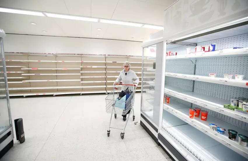 Une cliente face à des allées dénudées dans un magasin Sainsbury's à Harpenden, au Royaume-Uni.