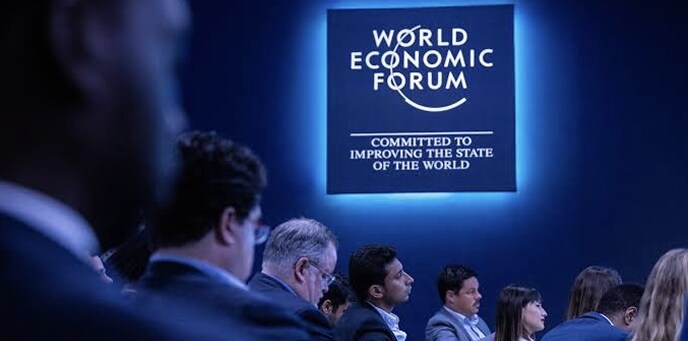 世界経済フォーラムのサインの前に座るデリゲートたち