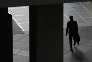 東京のビジネス街にある商業ビルの廊下を歩く男性