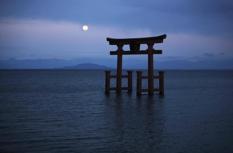 A Shinto shrine gate, with the moon behind it, is seen amidst Japan's largest lake, Lake Biwa, in Takashima, Shiga prefecture in western Japan. REUTERS/Toru Hanai