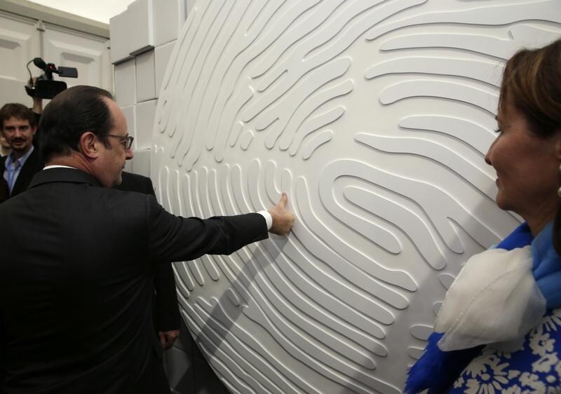 French President Francois Hollande puts his thumbprint on a wall at the Nicolas Hulot Foundation stand in the Climate Generations area during the World Climate Change Conference 2015 (COP21) at Le Bourget, near Paris, France, December 1, 2015. At R, French Minister for Ecology, Sustainable Development and Energy Segolene Royal.        REUTERS/Philippe Wojazer - RTX1WNID
