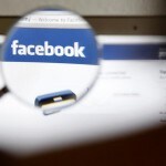 En esta ilustración fotográfica, se ve el logotipo de Facebook en la pantalla de un ordenador a través de una lupa sostenida por una mujer en Berna