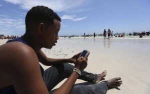 A Somali man browses the internet on his mobile phone at a beach along the Indian Ocean coastline in Mogadishu