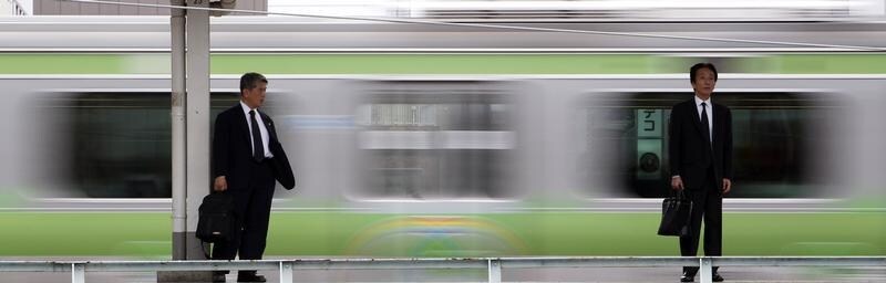 Los viajeros esperan en el andén mientras pasa un tren por una estación de la línea Yamanote en Tokio