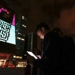 Un niño usa un iPad para jugar a un juego que se proyecta sobre el edificio Fiesp durante la exposición «Play!» en la avenida Paulista